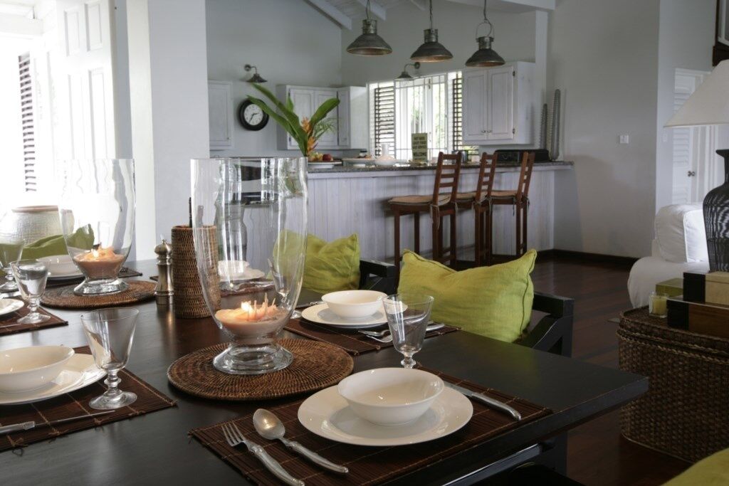 A dining area with a dark wooden table set for a meal, surrounded by chairs with yellow cushions.