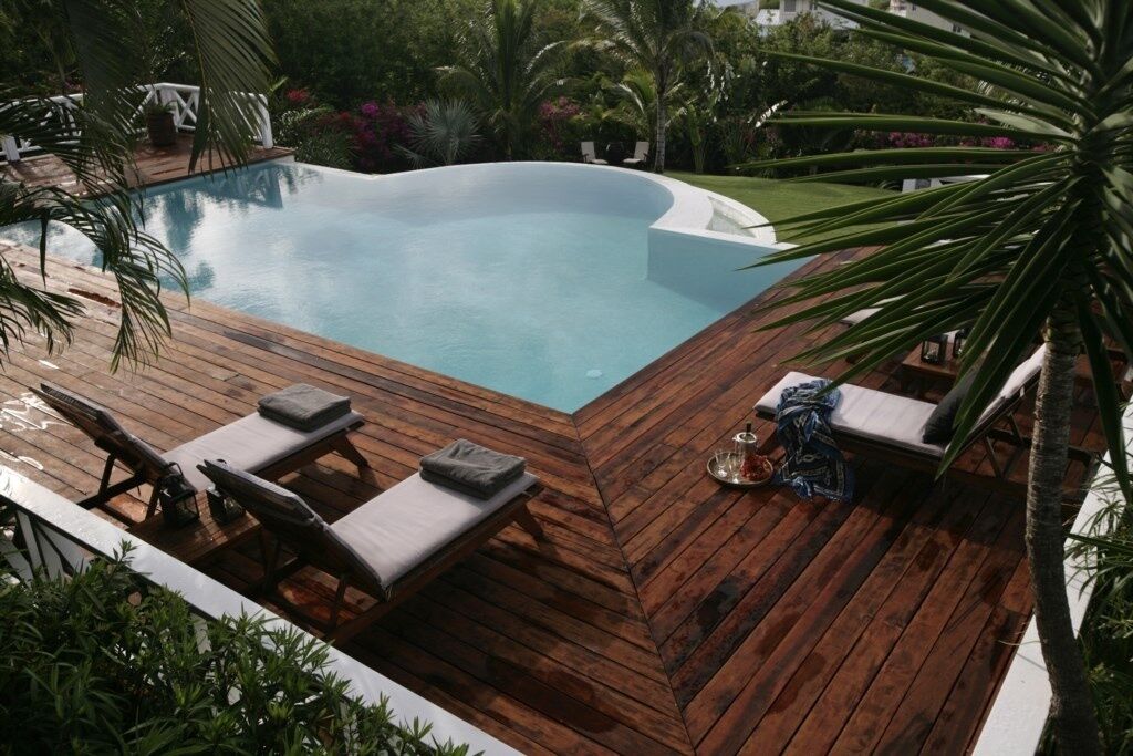 Une piscine avec une terrasse en bois et des chaises longues.