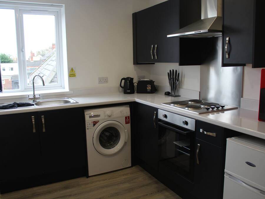 A compact kitchen with a washing machine, oven, and a microwave.