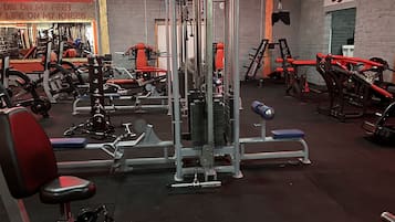 Uma academia com diversos equipamentos de exercício, incluindo máquinas de peso e bancos.