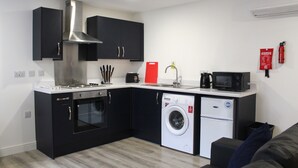 Une cuisine compacte équipée d’une cuisinière, d’un four, d’un four à micro-ondes et d’un lave-linge.
