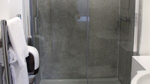Une salle de bain moderne avec une douche à parois de verre, des toilettes blanches et un lavabo.