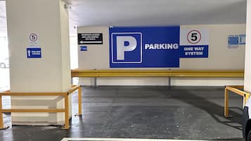 A parking garage with one-way signs, speed limit signs, and a speed camera warning.