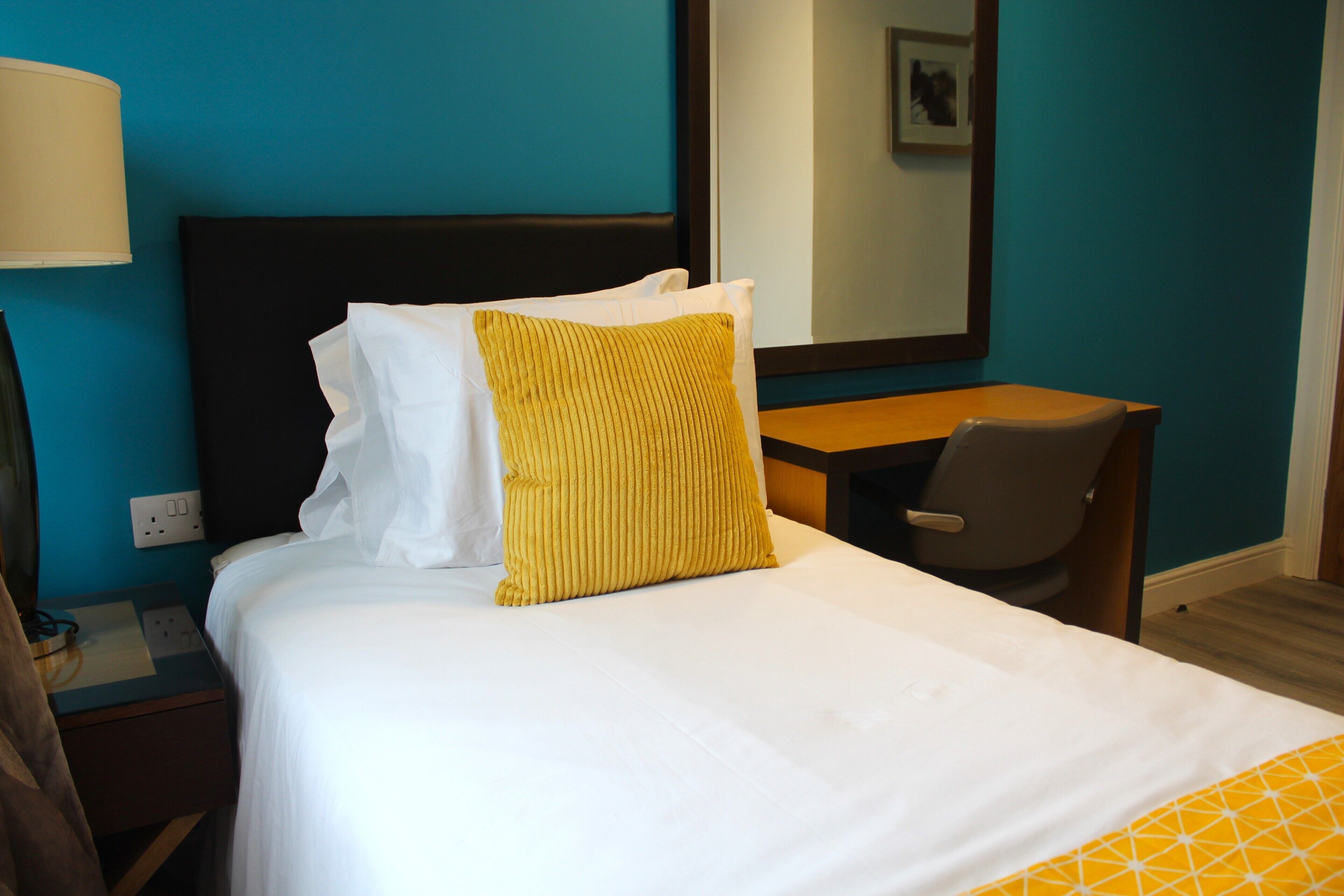 A hotel room with a bed, a desk, and a chair.