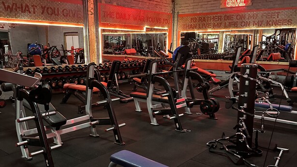 Une salle de sport équipée de divers appareils d’exercice, notamment des bancs et des machines de musculation.