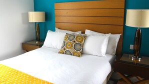 Une chambre d’hôtel avec un grand lit, deux tables de chevet avec des lampes et un mur d’accent bleu.