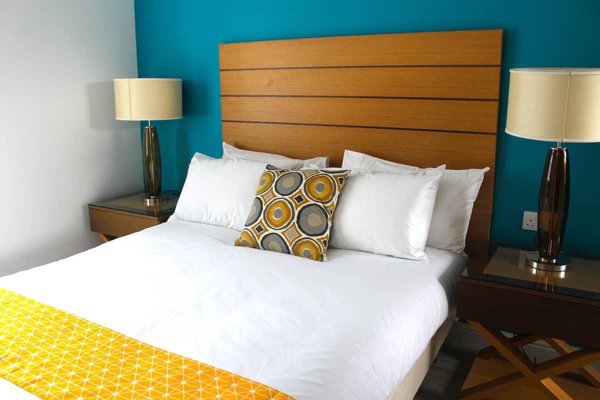 A hotel room with a large bed, two bedside tables with lamps, and a blue accent wall.