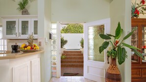 Una cocina con un frutero, una cafetera y una planta grande.