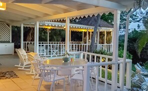 A covered outdoor seating area with white chairs and a round table, surrounded by a white railing and a glass enclosure. - Beautiful 2-bed Cliffside Villa - Saline Reef 2 Bedroom Villa by RedAwning (Gros Islet)