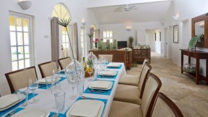 A dining area with a long table set for a meal, chairs, a television, and a wooden cabinet. - 2-bed Villa With Uninterrupted Sea Views - Equinox 2 Bedroom Villa by RedAwning (Gros Islet)