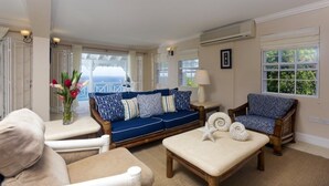 A living room with a blue sofa, beige armchairs, a coffee table, and a view of the outdoors.