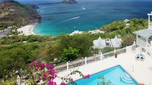A large house with a swimming pool, a balcony, and a view of the ocean.