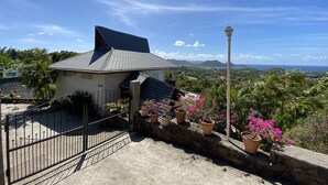 Une maison avec un toit en pente, un mur en pierre et un portail en métal.