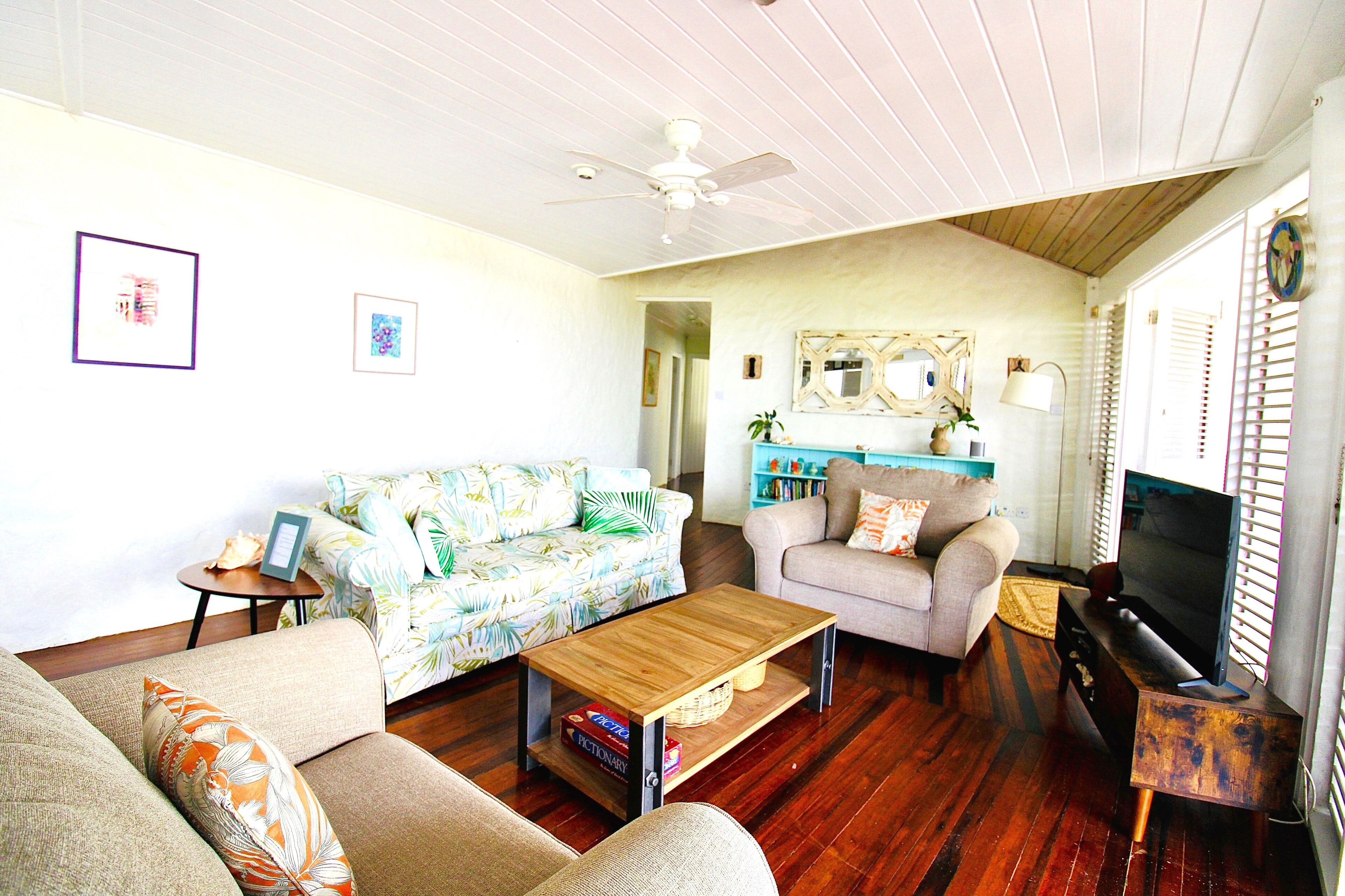 A living room with a wooden coffee table, two sofas, a television, and a ceiling fan.