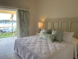 Relax in a spacious room with a large bed, nightstand, and marina view through a large window.
