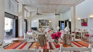 A dining area with a long table set for a meal, a bookshelf in the background, and a ceiling fan. - Sprawling three bedroom villa - Tamarind Villa 3 Villa by RedAwning (Gros Islet)