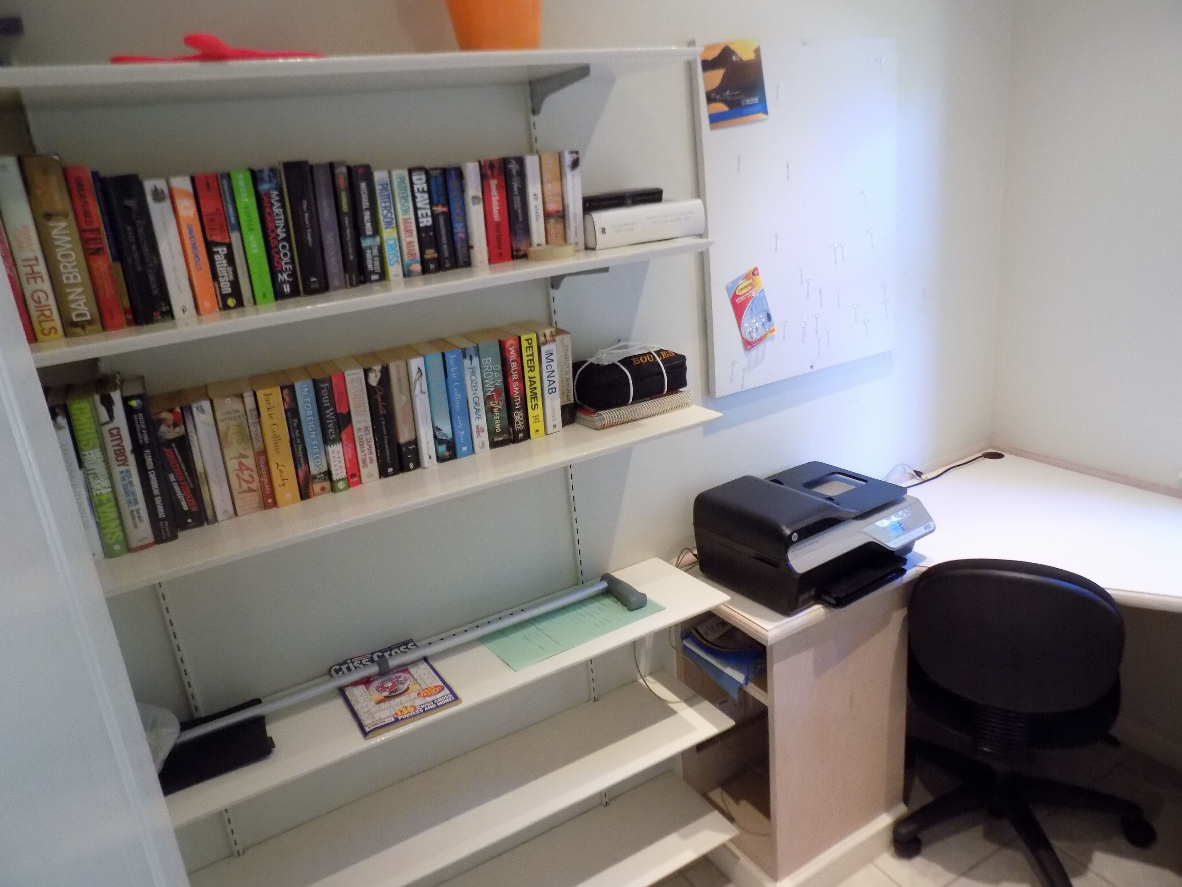 A home office with a desk, chair, and shelves filled with books.