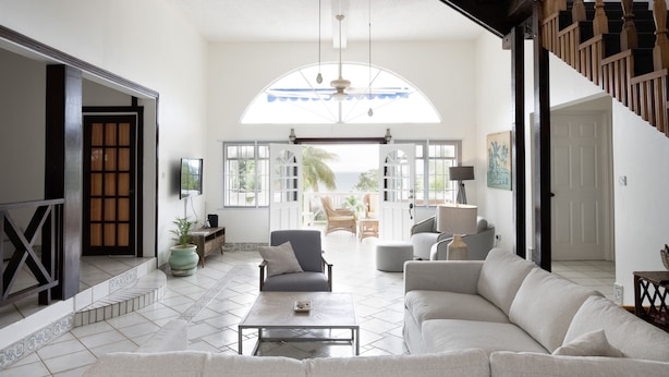 A spacious living room with a large window, a staircase, and a view of the outdoors. - Two Bedroom Villa with Private Pool Near to Beaches - Date House 2 Villa by RedAwning (Gros Islet)