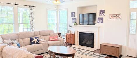 A living room with a sofa, a round coffee table, a fireplace, and a television.
