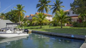 A marina with a boat docked, surrounded by palm trees and a building with a red roof. - The Anchorage #5 a 2 bedroom Waterfront Condo in Rodney Bay 2 Condo by RedAwning (Gros Islet)