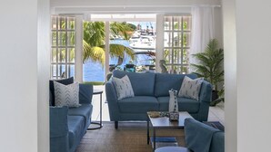 A living room with a blue sofa set, a coffee table, and a view of the ocean. - The Anchorage #5 a 2 bedroom Waterfront Condo in Rodney Bay 2 Condo by RedAwning (Gros Islet)