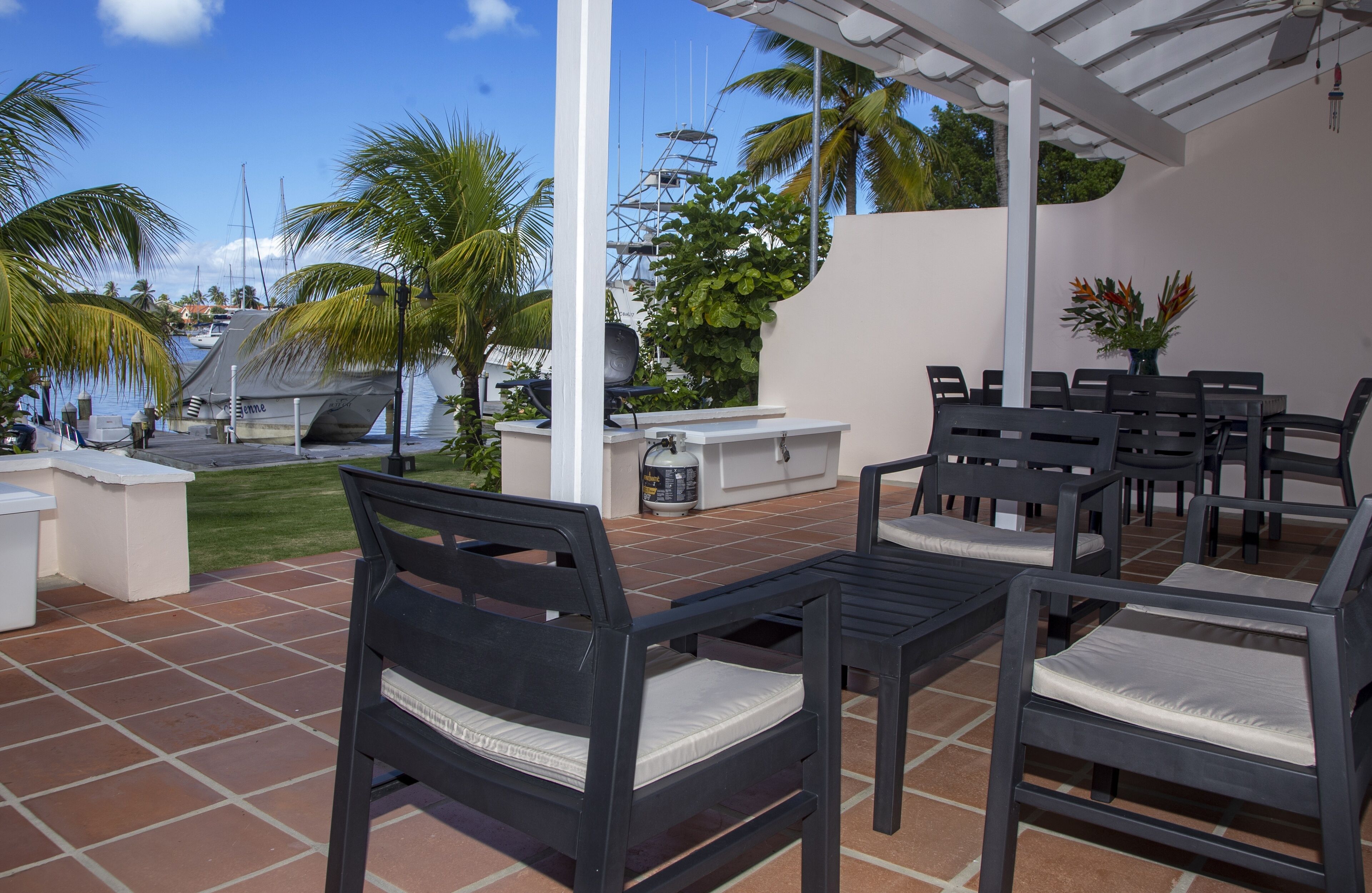 Un patio al aire libre con una parrilla, zona de estar y vistas al puerto deportivo.