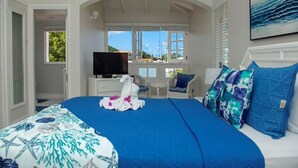 A bedroom with a large bed, a TV, a desk, and a view of the sea. - The Anchorage #5 a 2 bedroom Waterfront Condo in Rodney Bay 2 Condo by RedAwning (Gros Islet)