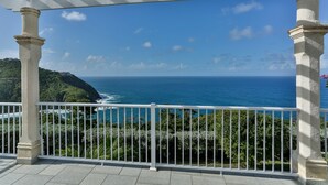A balcony with a white railing, overlooking a coastal landscape with a clear blue sky and ocean. - Cayman Villa - Contemporary 4 bedroom Villa with Stunning Ocean Views 4 Villa by RedAwning (Gros Islet)
