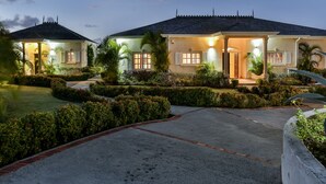 A two-story house with a covered porch and a well-maintained garden. - Cayman Villa - Contemporary 4 bedroom Villa with Stunning Ocean Views 4 Villa by RedAwning (Gros Islet)