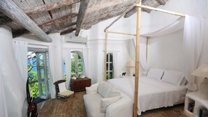 A room with a four-poster bed, a sofa, and a wooden floor. - Smuggler's Nest - Exotic & Romantic Villa 2 Bedroom Villa by RedAwning (Gros Islet)