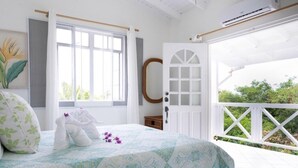 A bedroom with a bed, a window, a door, and a balcony.