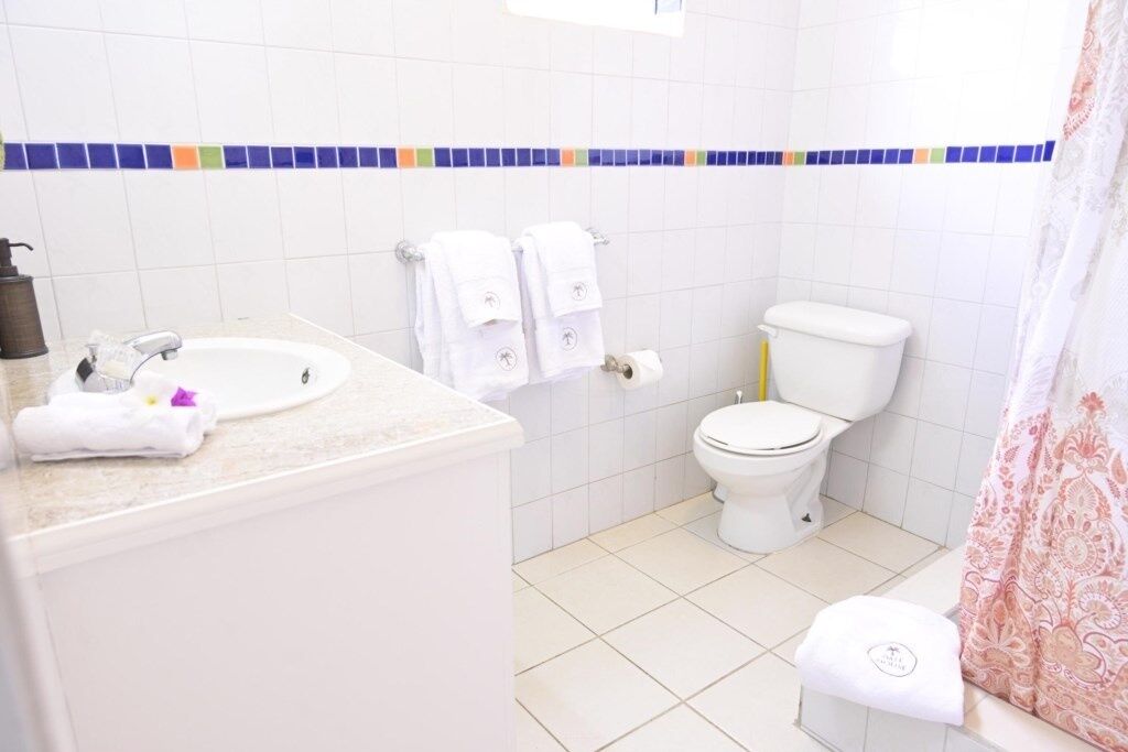 A bathroom with a white sink, toilet, and shower curtain.