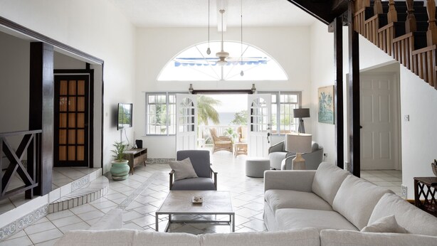 A spacious living room with a large window, a staircase, and a view of the outdoors.