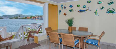 Un comedor con mobiliario de mimbre, vistas al mar y decoración de peces en la pared.