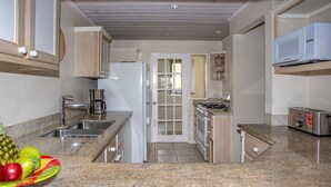 A compact kitchen with a sink, stove, microwave, and a coffee maker.