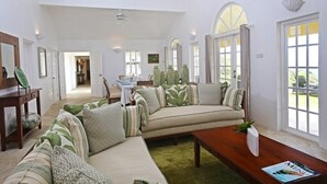 A spacious living room with a sectional sofa, a wooden coffee table, and a dining area in the background.