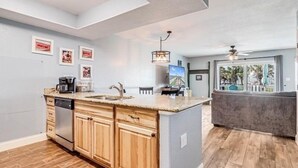 A modern kitchen with wooden cabinets, a granite countertop, and a built-in dishwasher. - Sunset Breeze 3 Bedroom Condo by RedAwning (Rockport)