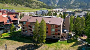 A multi-story hotel with a red roof, surrounded by greenery and mountains in the background. - Sl299 Spruce Lodge 2br 2ba 2 Bedroom Condo by RedAwning (Copper Mountain)