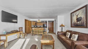 A spacious living room with a brown leather sofa, a coffee table, and a dining area with wooden furniture. - Sl299 Spruce Lodge 2br 2ba 2 Bedroom Condo by RedAwning (Copper Mountain)