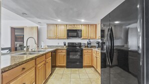 A modern kitchen with wooden cabinets, a black refrigerator, a microwave, and a stove. - Sl299 Spruce Lodge 2br 2ba 2 Bedroom Condo by RedAwning (Copper Mountain)