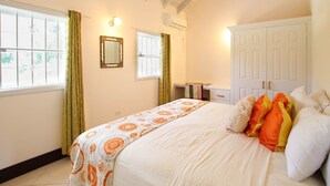 A bedroom with a bed, a wardrobe, a mirror, and a window with curtains.