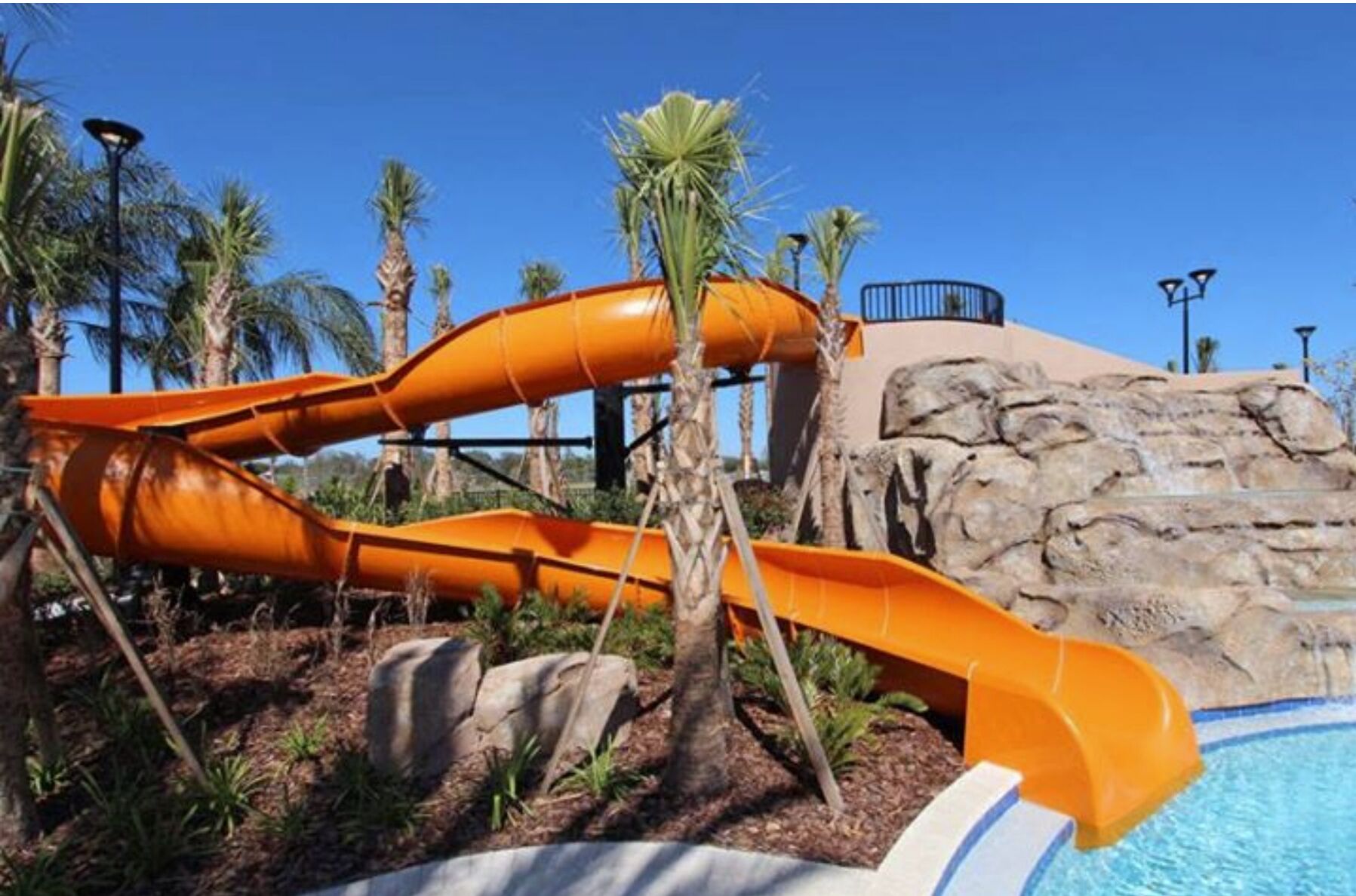 Un toboggan aquatique avec un décor rocheux et des palmiers.