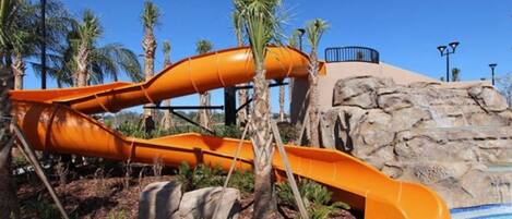 Un toboggan aquatique avec un décor rocheux et des palmiers.