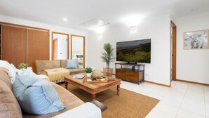 Ein Wohnzimmer mit einer Couch, einem Couchtisch, einem Fernseher und Kunstwerken.