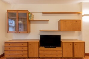 Cozy living space with cabinet, flat-screen TV, and ample storage.