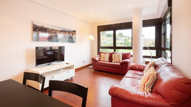 Una sala de estar moderna con televisor, una mesa de comedor y dos sofás.