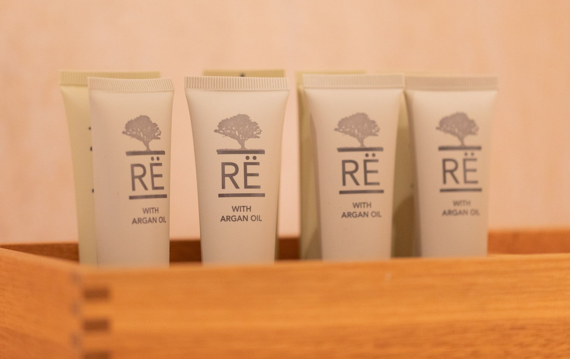 Quatre tubes de crème étiquetés « RE à l’huile d’argan » dans une boîte en bois.