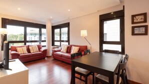Un salón moderno con un sofá de cuero rojo, una mesa de comedor de madera y ventanas amplias.