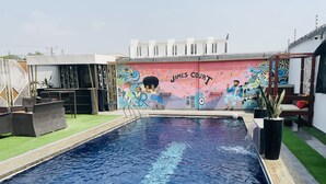 A swimming pool with a mural titled "James Court" and outdoor seating. - James Court Hotel & Luxury Apartments (Lekki)