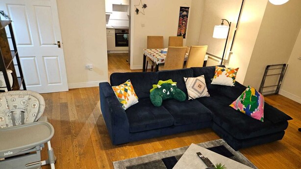 A living room with a dark blue sectional sofa, a small table with a plant, and a grey patterned rug.